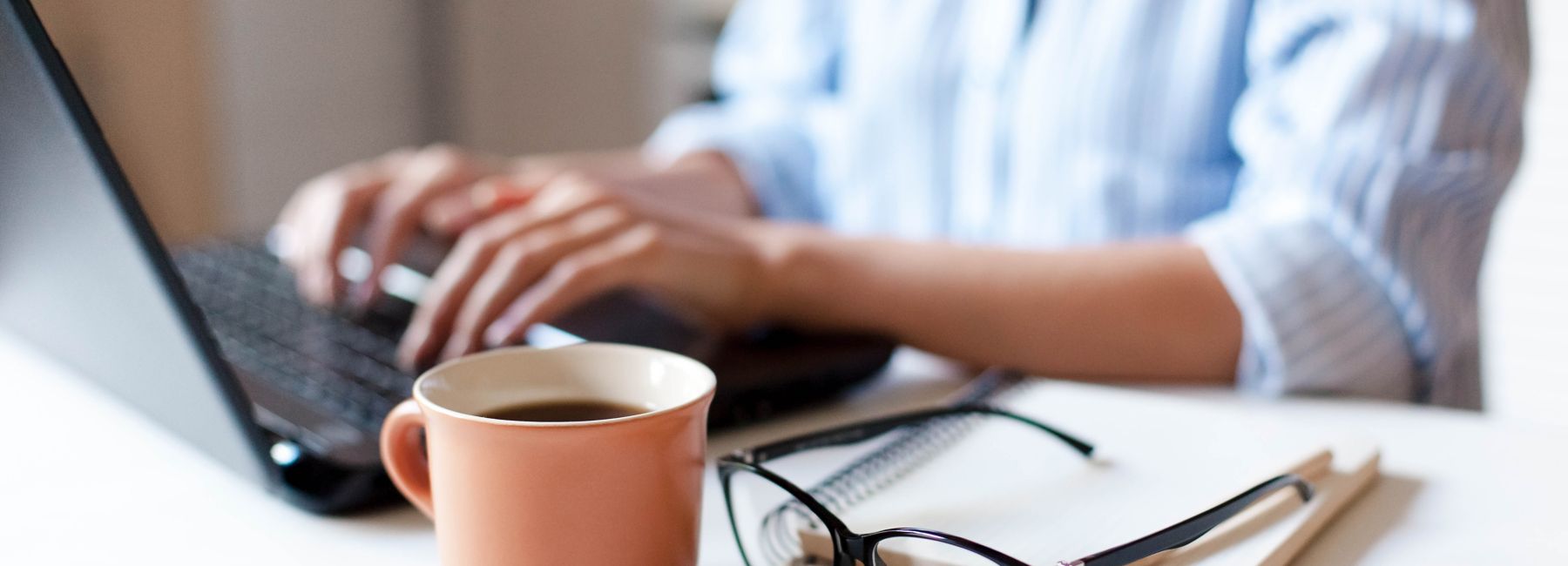 woman typing on laptop, with coffee and eyeglasses, Dell Technologies | DXC Technology